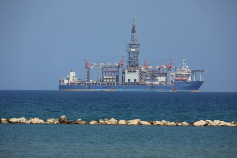 An offshore drilling rig floats on a calm sea with a clear blue sky in the background